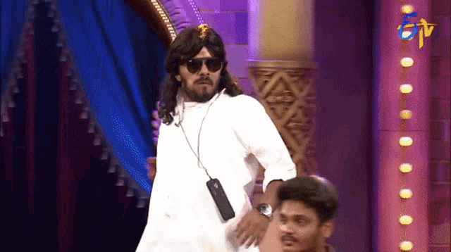 a man wearing a wig and sunglasses holds a cell phone