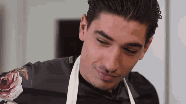 a man wearing an apron and a floral shirt is smiling