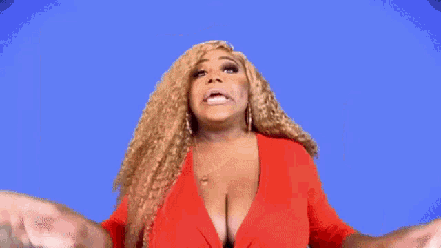 a woman in a red jacket is standing in front of an american flag and making a funny face .