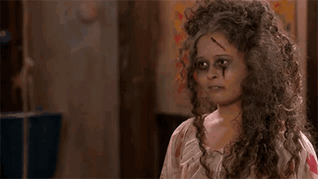a woman with curly hair and a scar on her face is dressed as a ghost .