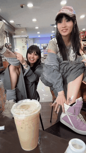two women are sitting at a table with a cup of coffee and a bottle of milk