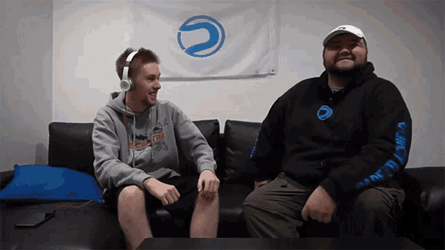 a man wearing headphones sits next to another man wearing a sweatshirt that says ' ec ' on it