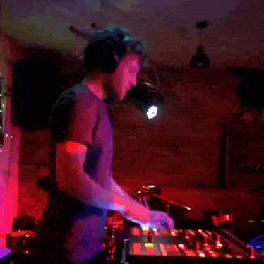 a man wearing headphones is playing music on a mixer in a dark room