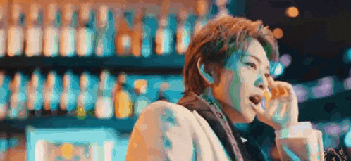 a man in a suit is sitting at a bar holding a drink .