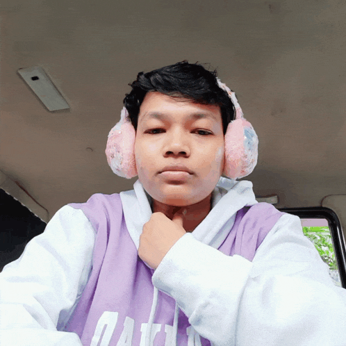 a young man wearing ear muffs and a purple shirt that says ' aa ' on it