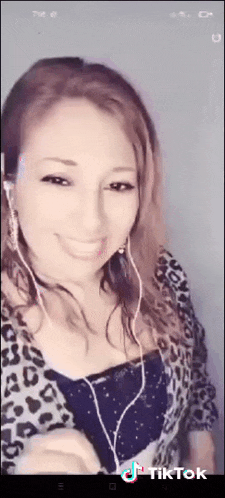 a woman wearing headphones and a leopard print top is smiling and looking at the camera .