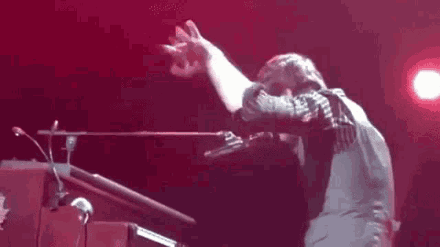 a man is playing a piano on a stage with his arm outstretched .