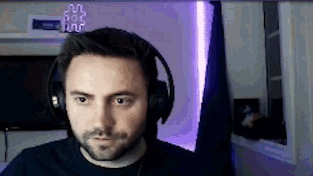 a man wearing headphones looks at the camera in front of a purple light