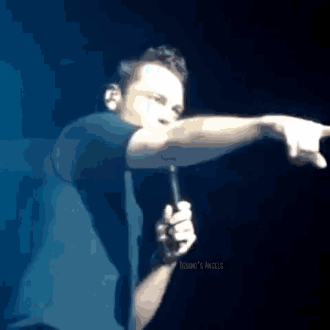 a man is holding a microphone in his right hand and pointing to the right