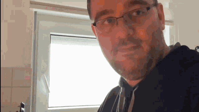 a man wearing glasses and a black hoodie looks at the camera
