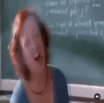 a woman with red hair is standing in front of a blackboard .