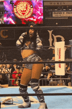 a woman in a wrestling ring stands in front of a sign that says women on it