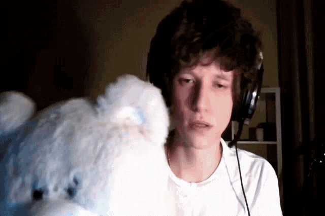 a man wearing headphones holds a teddy bear