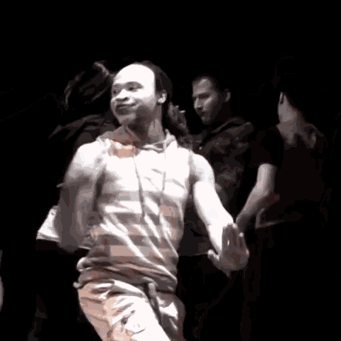 a group of people are dancing in a dark room and one of them is bald