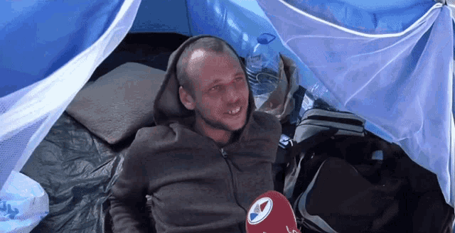 a man laying in a tent with a microphone that says sky news