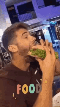 a man eating a sandwich with the word food written on his shirt