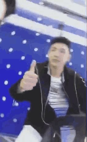 a man in a black jacket is giving a thumbs up sign