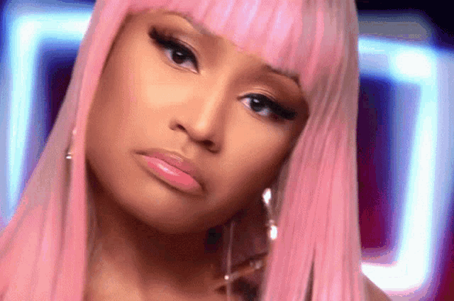 a close up of a woman 's face with pink hair .