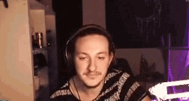a man wearing headphones is sitting in front of a computer screen in a dark room .