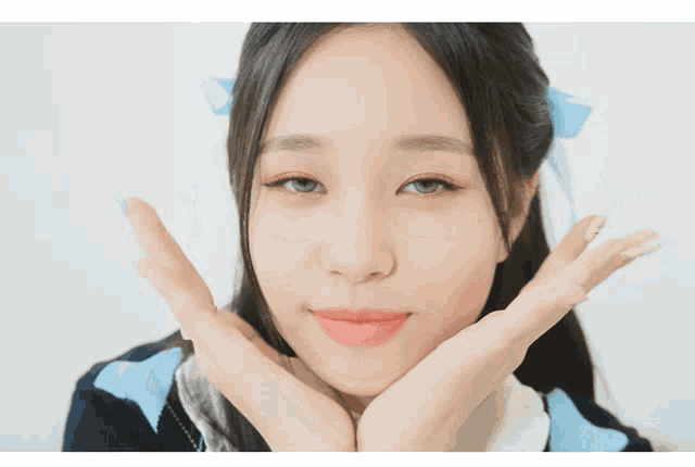 a close up of a woman 's face with her hands on her cheeks