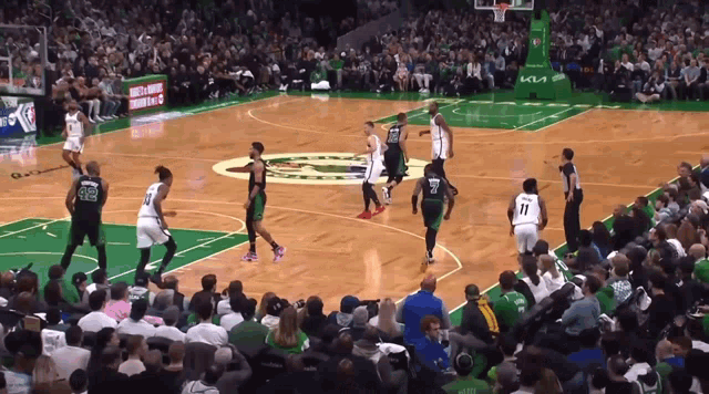 a basketball game being played in front of a crowd with a kia ad