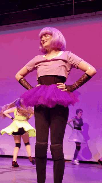 a woman in a purple tutu is dancing on a stage