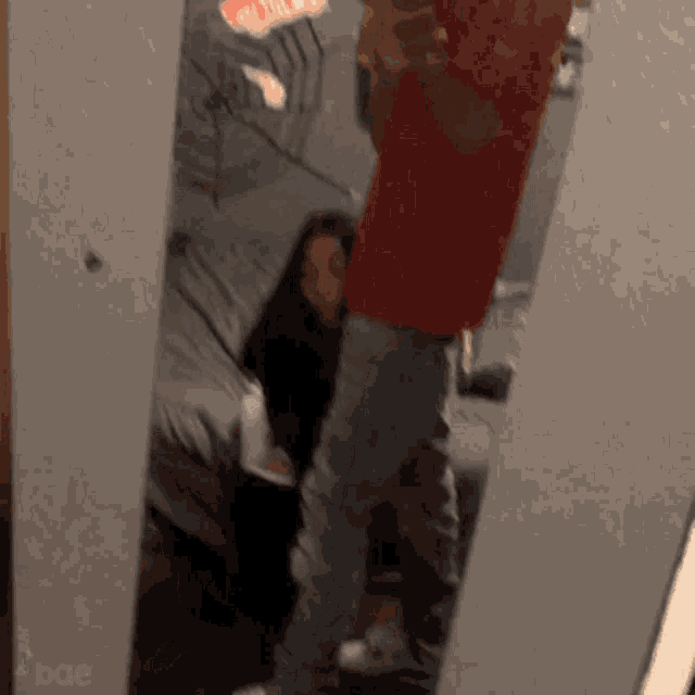 a man in a red shirt is taking a selfie in a mirror