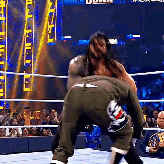 a wrestler is carrying another wrestler in a wrestling ring with the word down on the screen