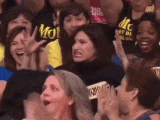 a crowd of people including a woman wearing a black shirt that says mon
