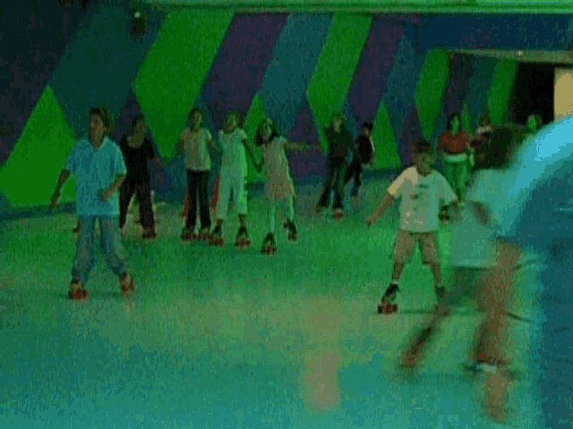 a group of people are rollerblading on a rink with green and purple walls .
