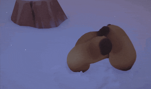 a brown stuffed animal is laying in the snow near a tree stump