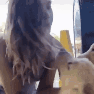 a woman is petting a small dog in front of a blue wall