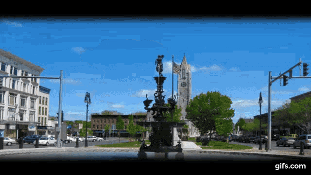a fountain with a clock tower in the background and a gifs.com logo on the bottom