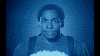 a man in a blue shirt is standing in front of a blue background and looking at something .