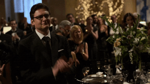 a man in a suit and tie is applauding at a party