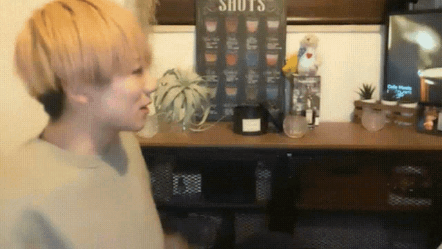 a man stands in front of a sign that says " shots "
