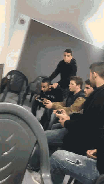 a group of young men are sitting in chairs and playing video games