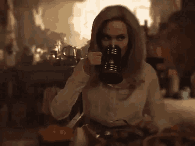 a woman is drinking a cup of coffee from a mug .