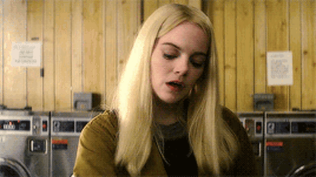 a blonde woman sitting in front of a laundromat