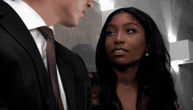 a man in a suit and tie stands next to a woman wearing earrings
