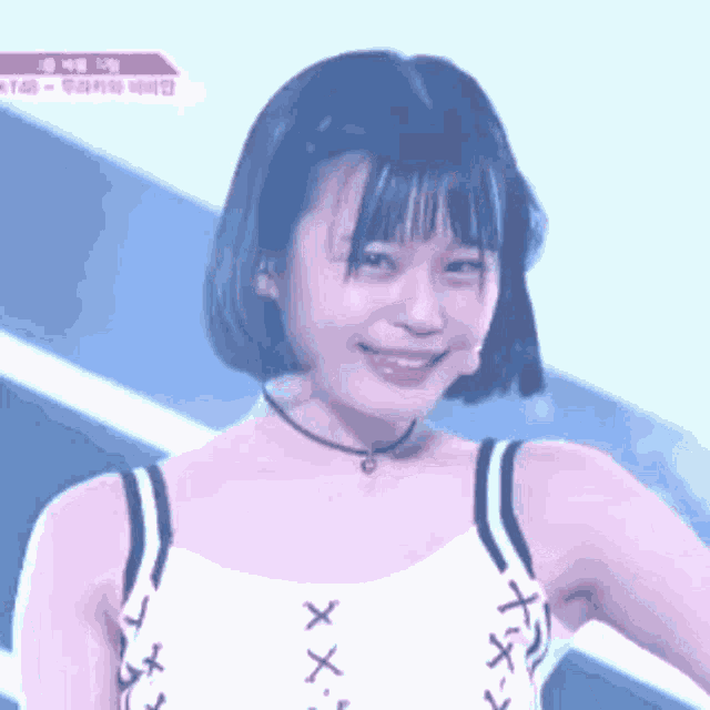 a girl with short hair is smiling and wearing a choker and a white tank top