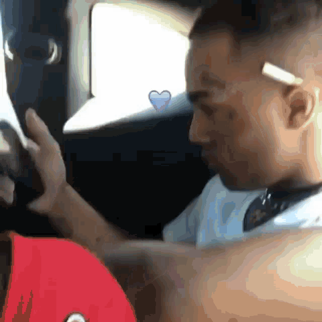 a man is sitting in the back seat of a car with a purple heart on the window .