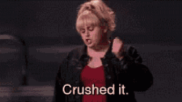 a woman in a red shirt and black jacket is dancing and saying `` crushed it . ''