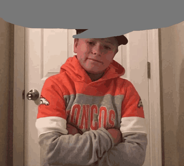 a boy wearing an orange and gray denver broncos sweatshirt