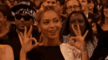 a woman is giving a peace sign in front of a crowd .