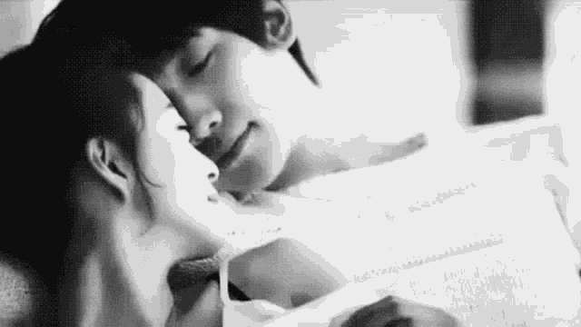 a black and white photo of a man and woman kissing .