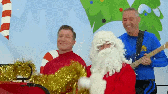 a man in a wiggle shirt is playing a guitar next to santa