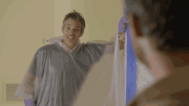 a man wearing a plastic cover looks at himself in the mirror