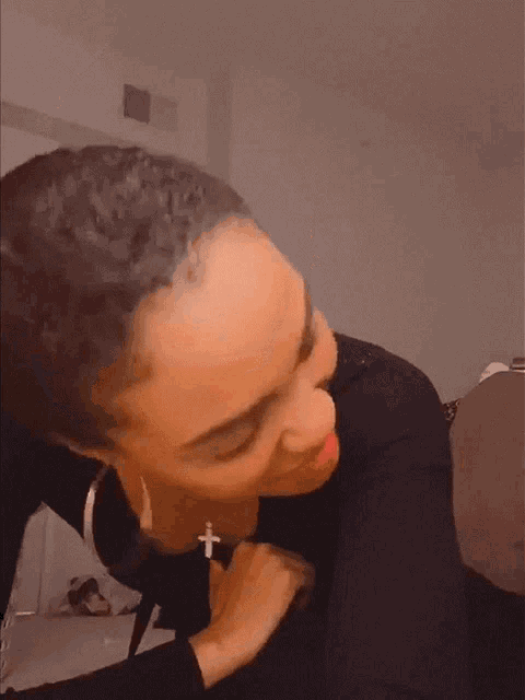 a woman wearing a black shirt and a cross necklace is making a funny face