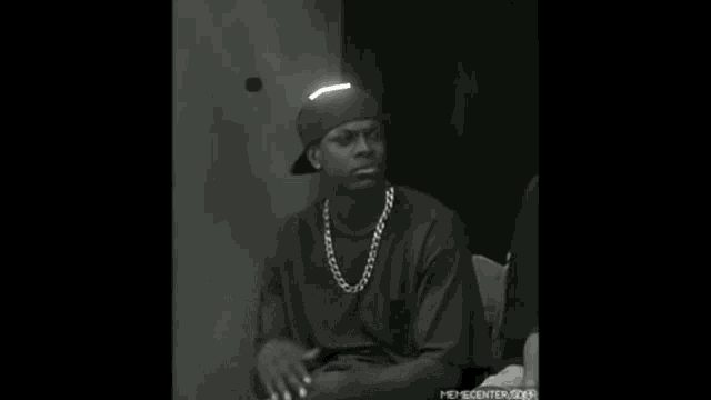 a black and white photo of a man wearing a chain and a beanie